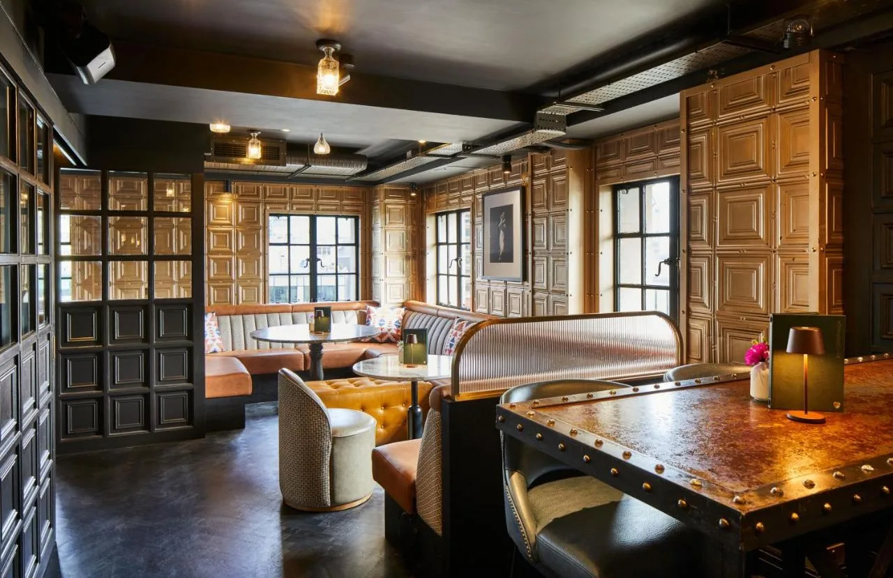 a restaurant with benches and tables in a room at The Rex - formerly Hotel Gotham in Manchester