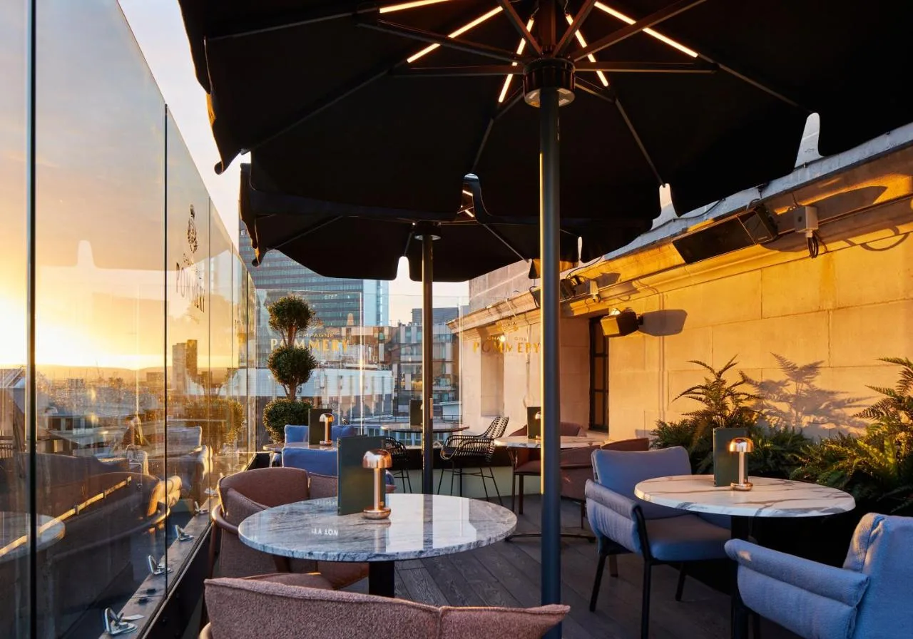 a patio with two tables and chairs and an umbrella at The Rex - formerly Hotel Gotham in Manchester