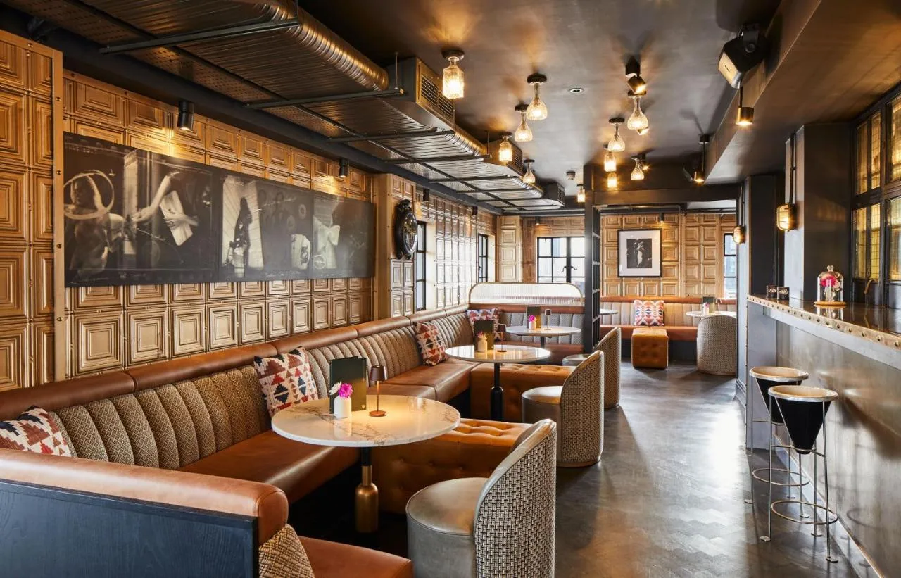 a restaurant with leather seats and tables and a bar at The Rex - formerly Hotel Gotham in Manchester