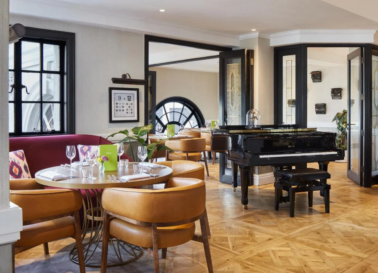 a restaurant with a piano and tables and chairs at The Rex - formerly Hotel Gotham in Manchester