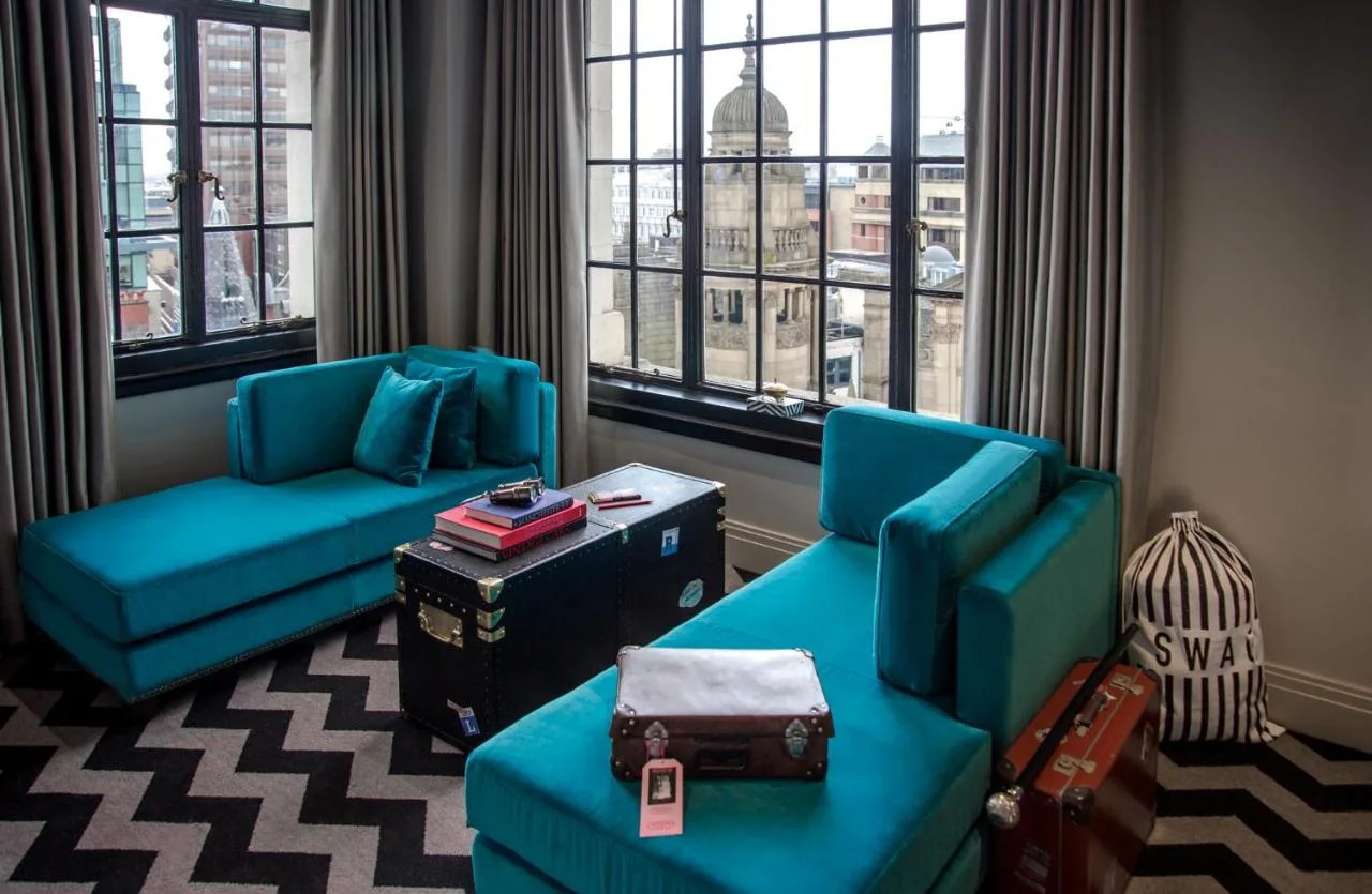 a living room with two blue chairs and a window at The Rex - formerly Hotel Gotham in Manchester